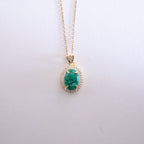 Gold necklace with a green gemstone pendant on a white background