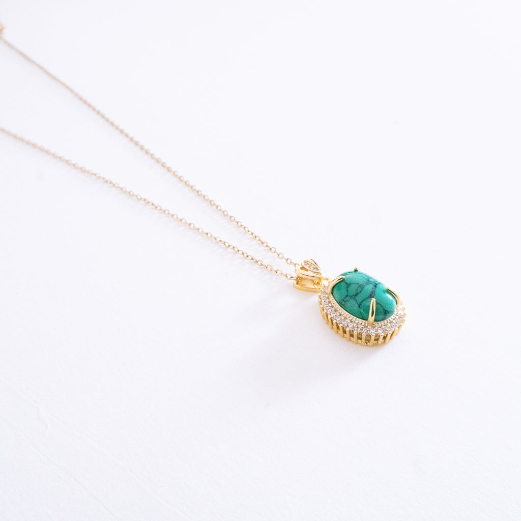 Gold necklace with a turquoise pendant on a white background