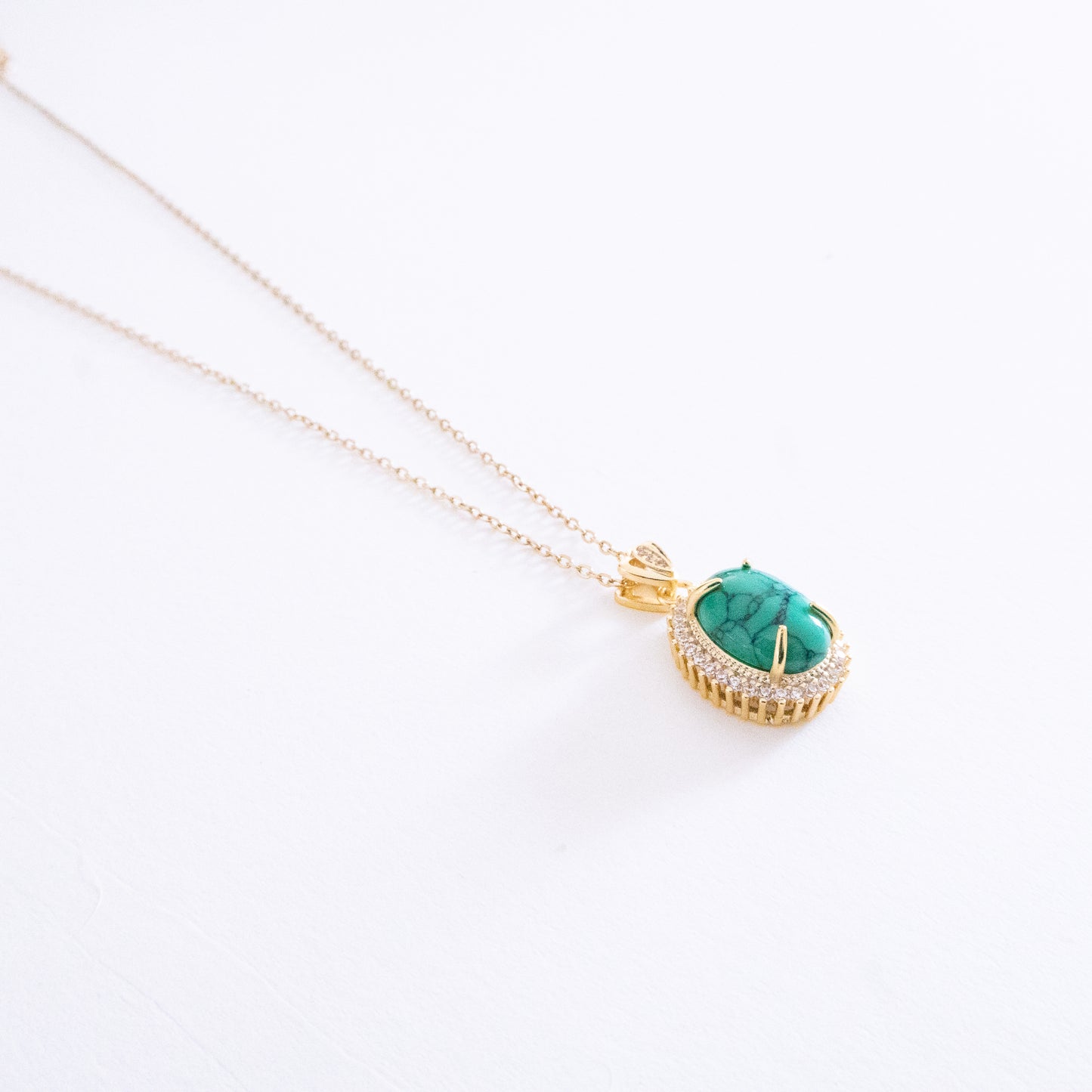 Gold necklace with a turquoise pendant on a white background
