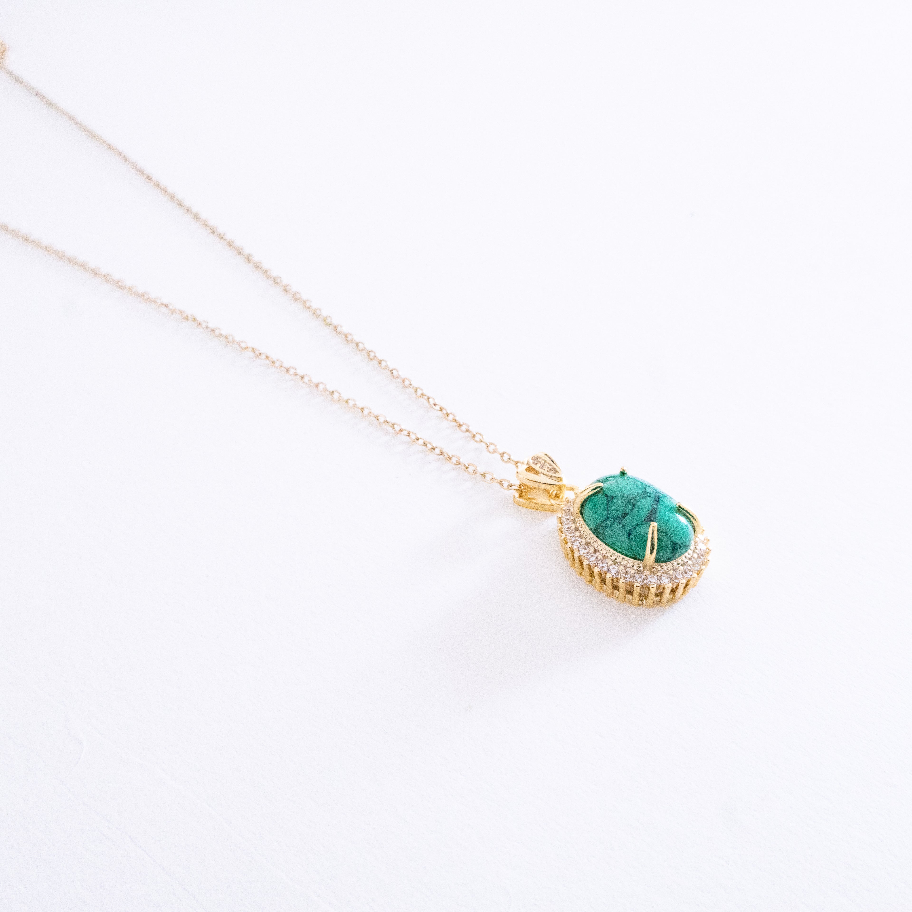 Gold necklace with a turquoise pendant on a white background
