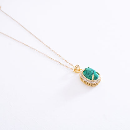 Gold necklace with a turquoise pendant on a white background