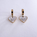 Heart-shaped earrings with gold and white design on a light gray background
