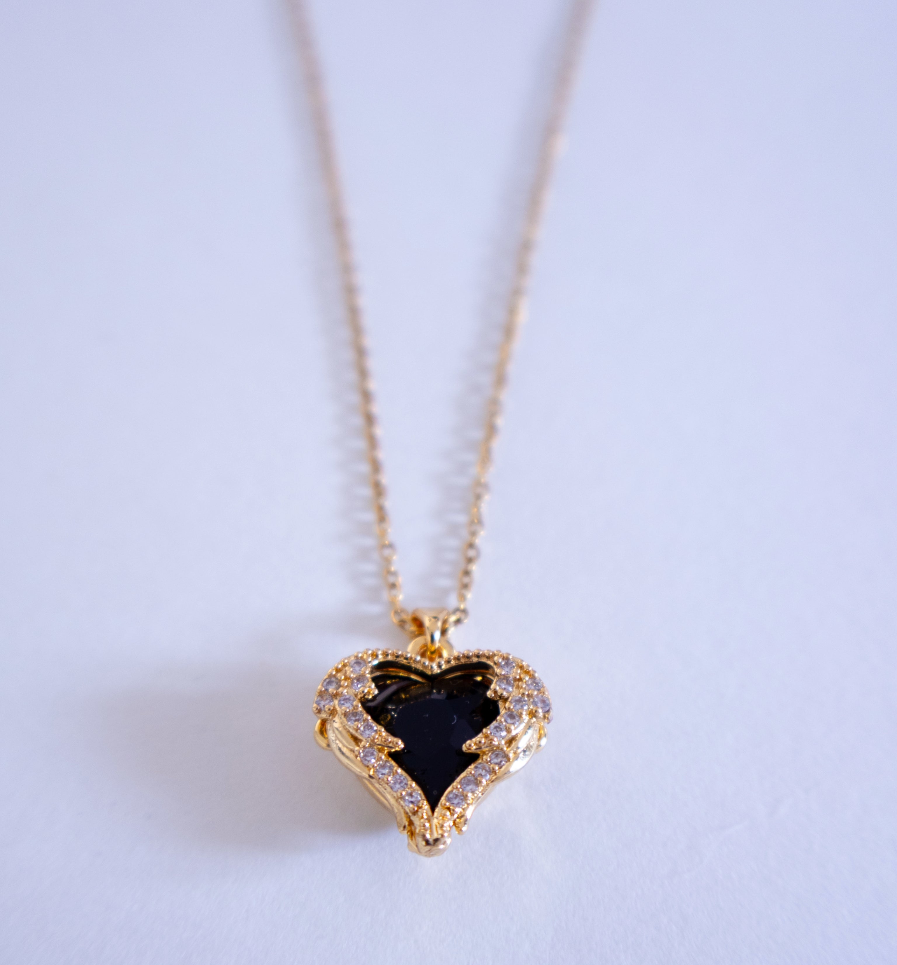 Heart-shaped necklace with a black stone on a light background