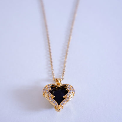 Heart-shaped necklace with a black stone on a light background