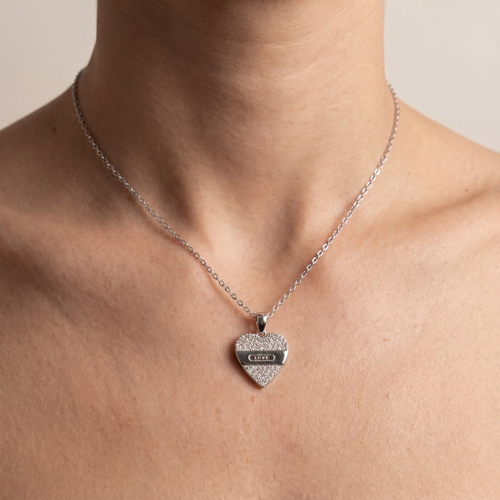 Heart-shaped pendant necklace on a person's neck with a neutral background