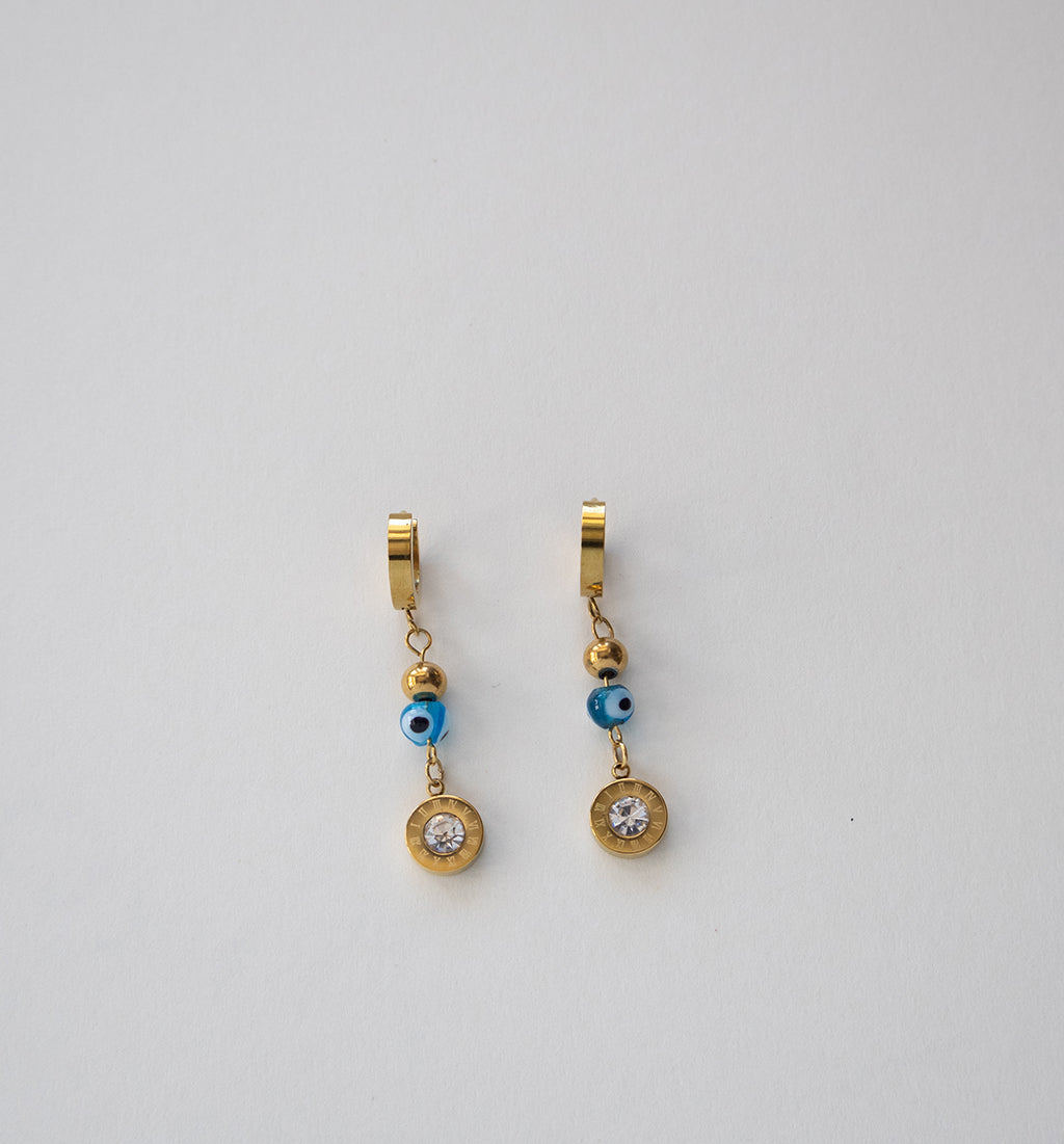 Brincos de argola dourados com contas de olho grego e pendentes de cristal.