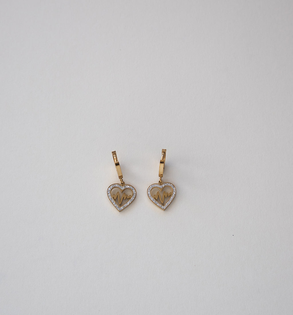 Brincos dourados de coração com bordas de cristal e monograma.