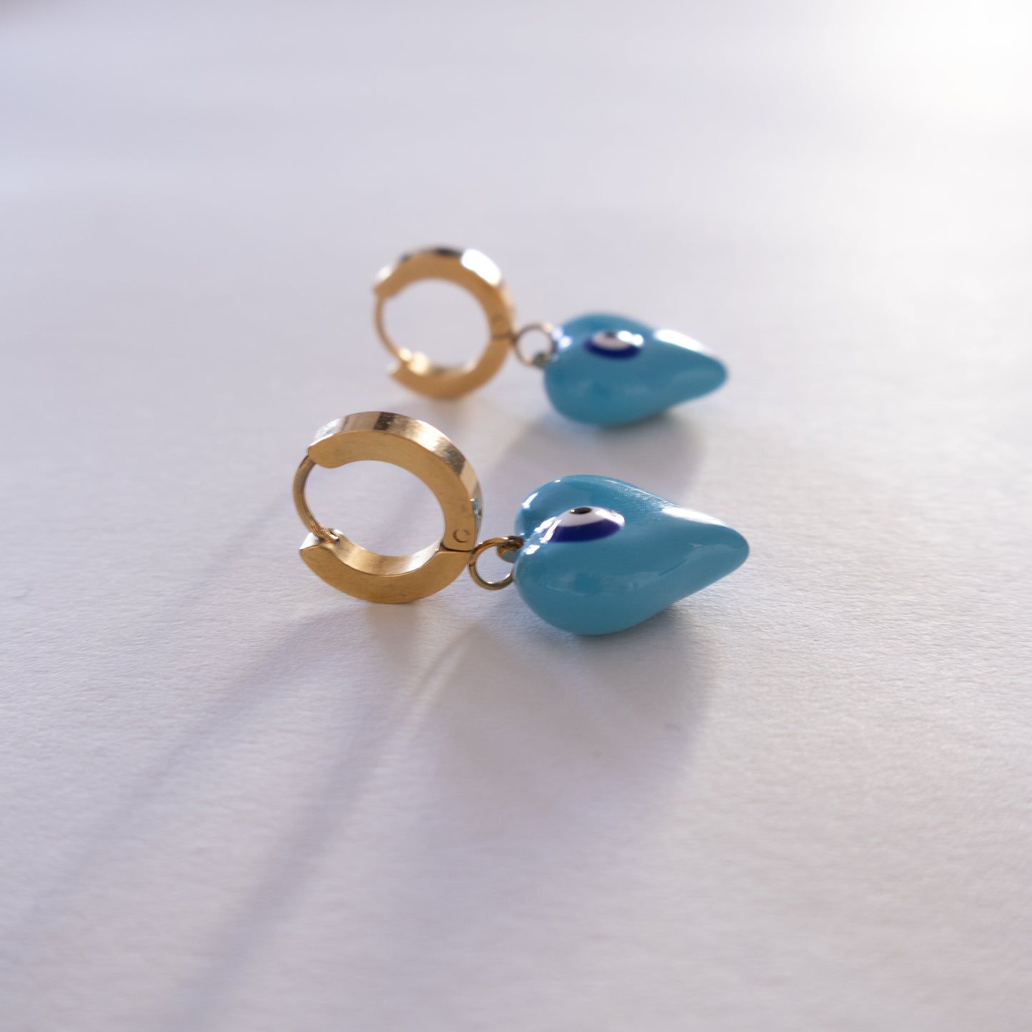 Pair of gold hoop earrings with blue teardrop charms on a white background