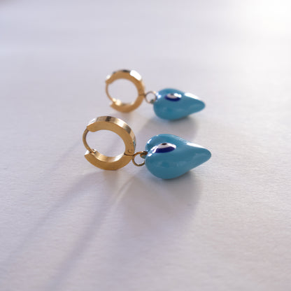 Pair of gold hoop earrings with blue teardrop charms on a white background