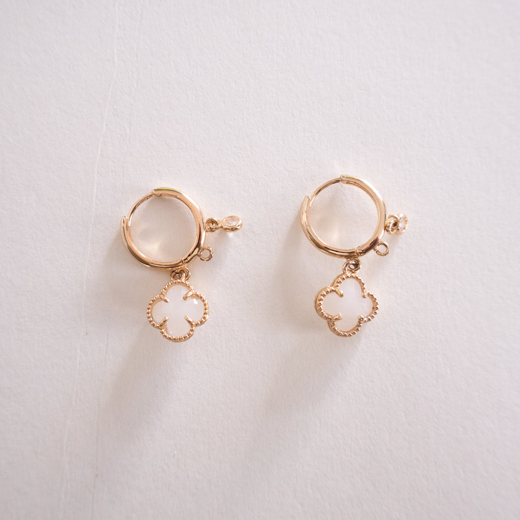 Pair of gold earrings with circular designs on a light background