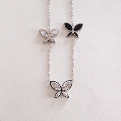 Butterfly-shaped pendants on a chain against a light background