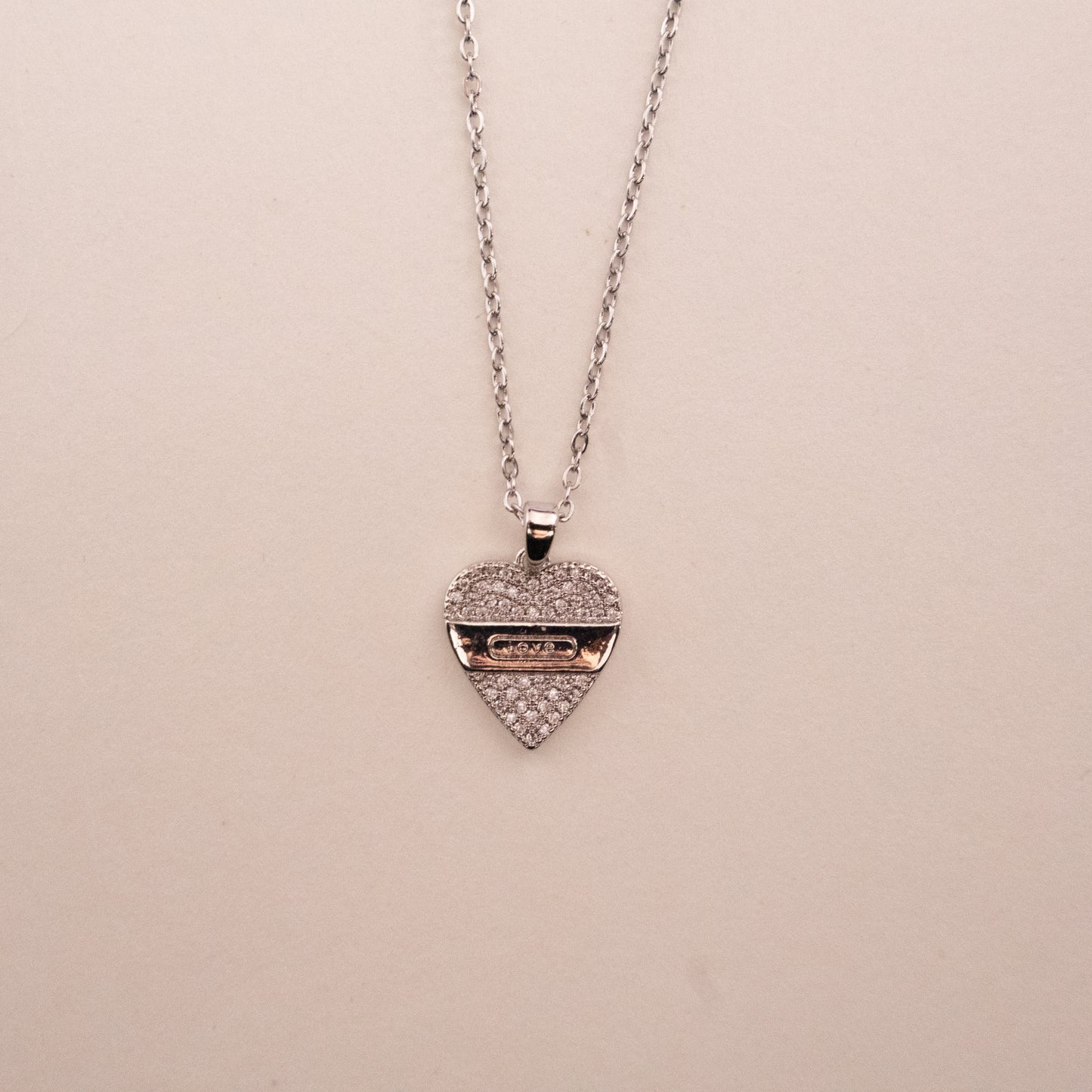 Gold necklace with a green gemstone pendant on a white background