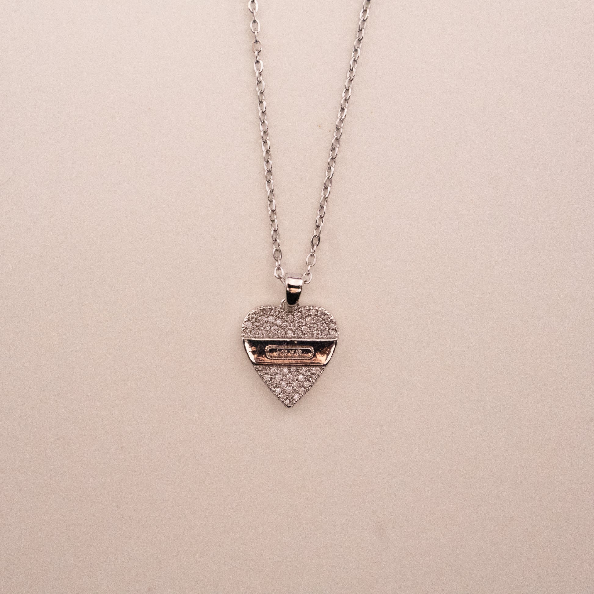 Gold necklace with a green gemstone pendant on a white background