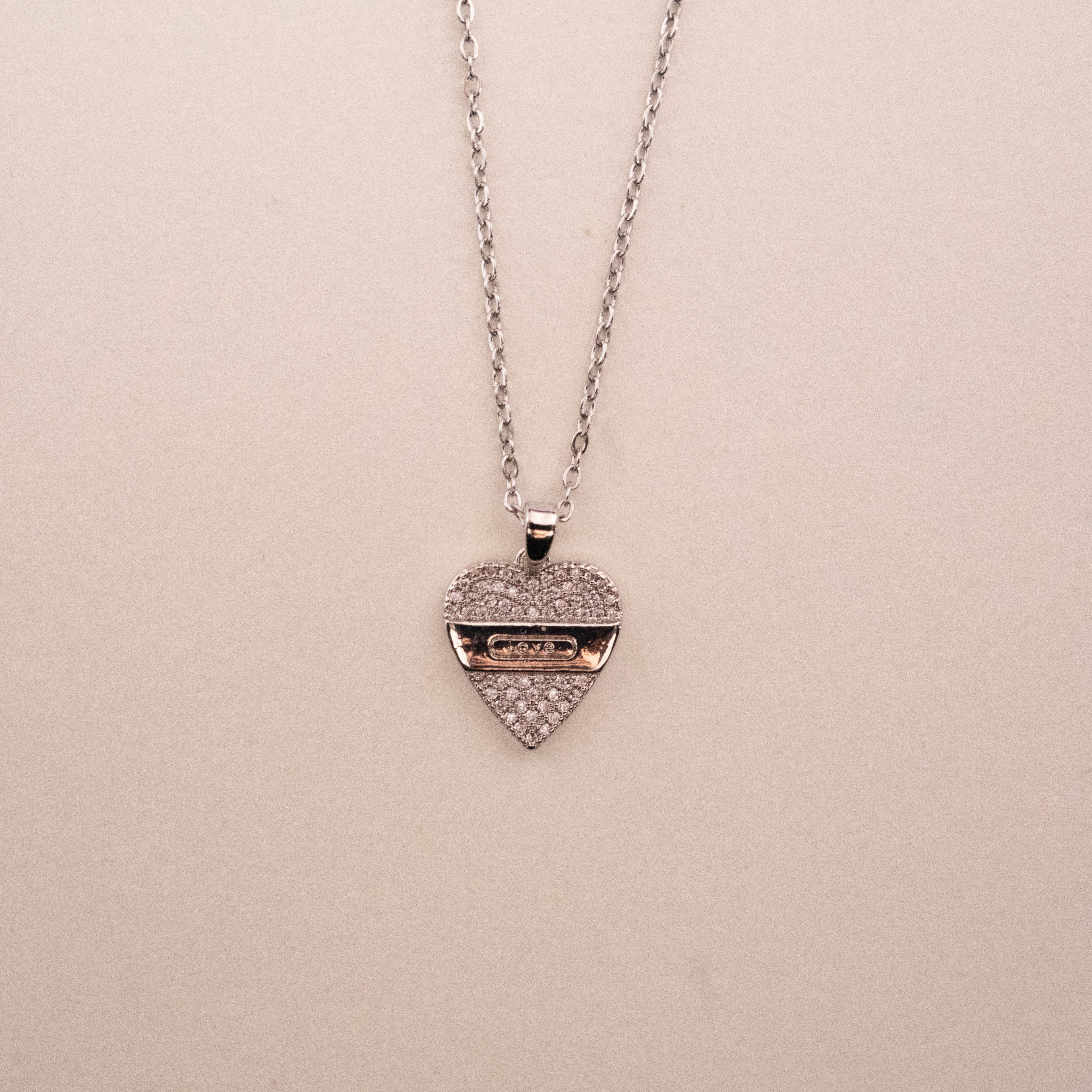 Gold necklace with a green gemstone pendant on a white background