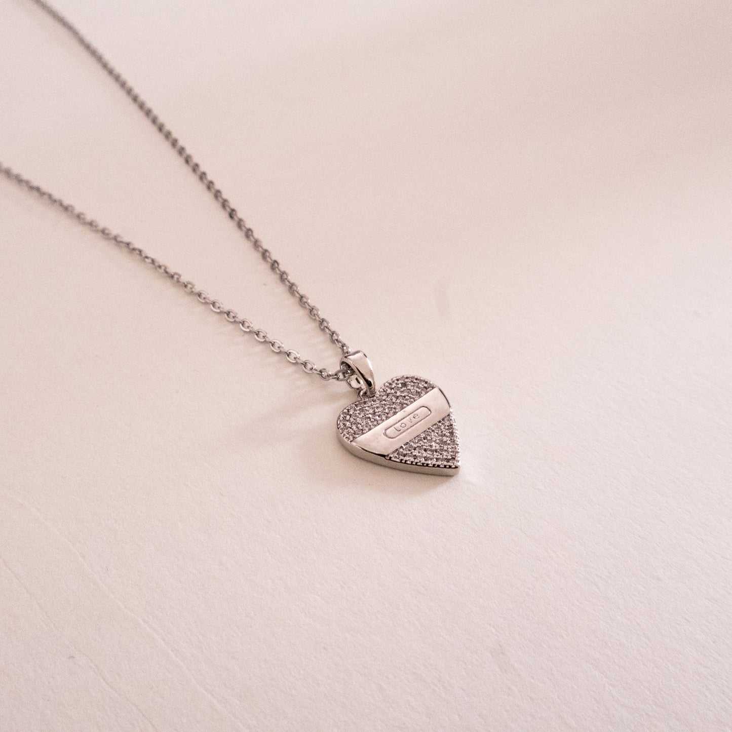 Gold necklace with a green gemstone pendant on a white background