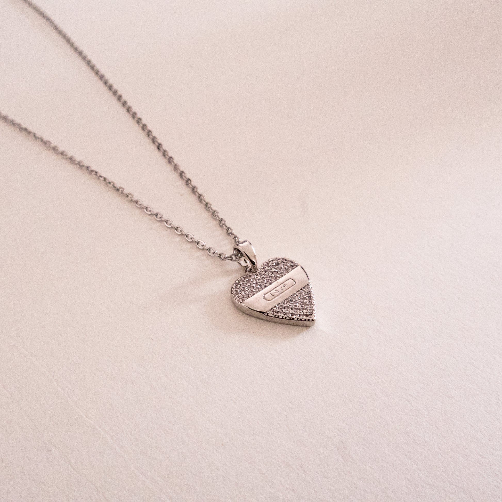 Gold necklace with a green gemstone pendant on a white background