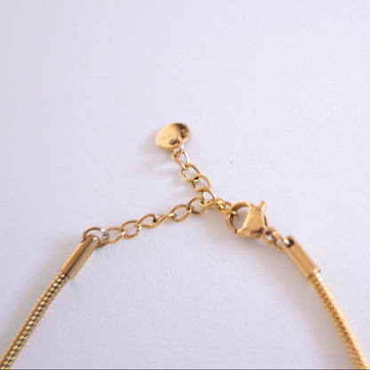 Gold chain bracelet on a light gray background