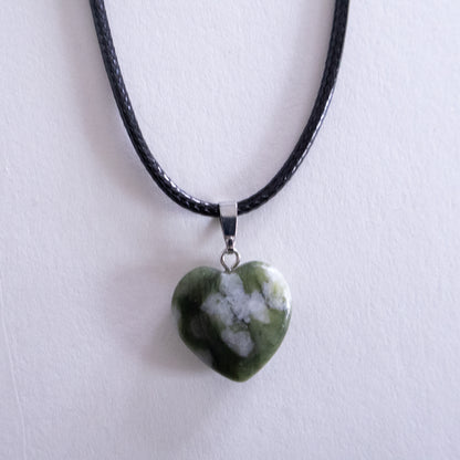 Heart-shaped green stone pendant on a black cord against a white background