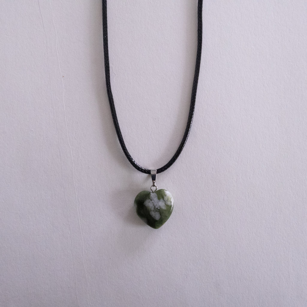 Silver necklace with a key pendant on a light pink background