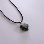 Silver necklace with a pendant on a light pink background