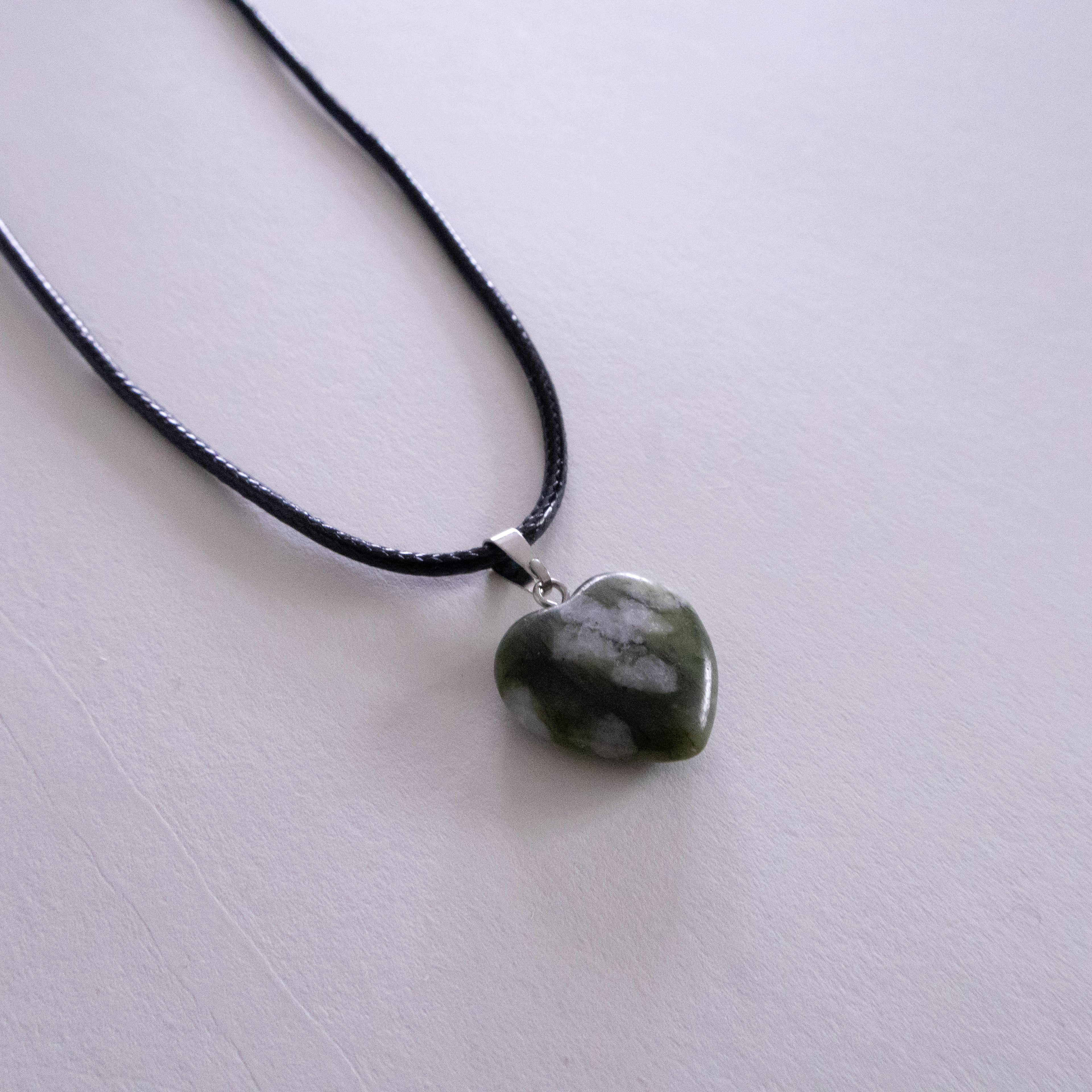 Silver necklace with a pendant on a light pink background