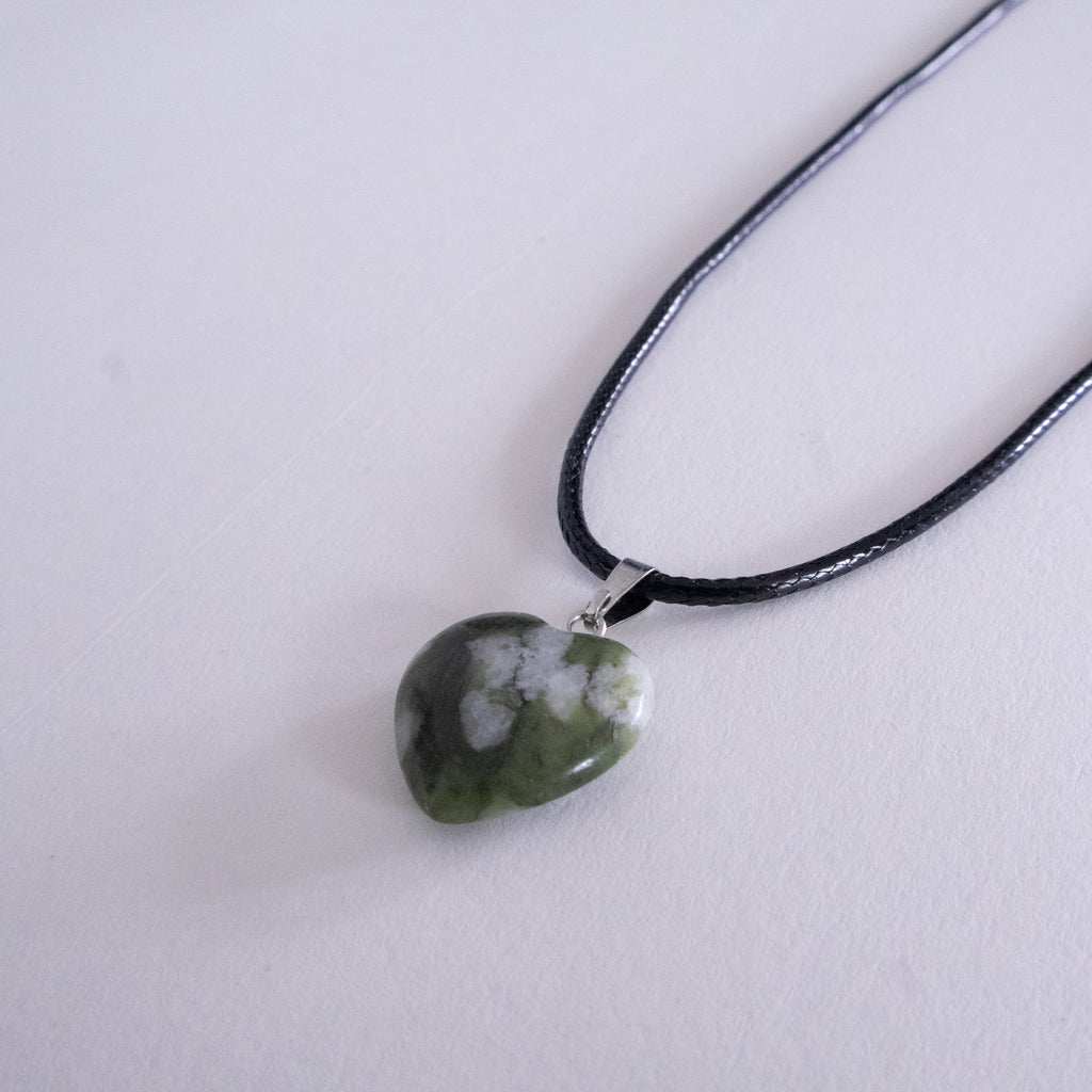 Silver necklace with a heart-shaped pendant on a beige background