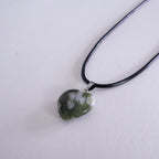 Silver necklace with a heart-shaped pendant on a beige background