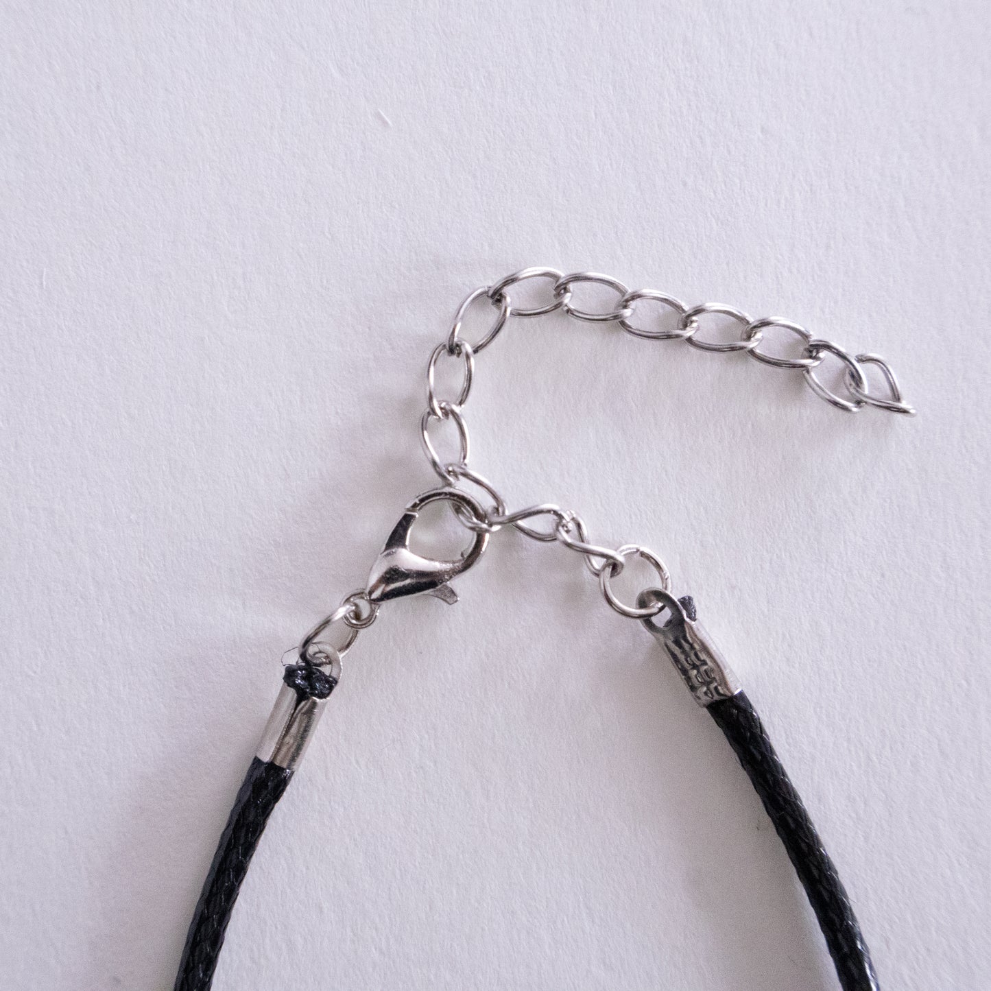 Silver necklace with a heart-shaped pendant on a beige background