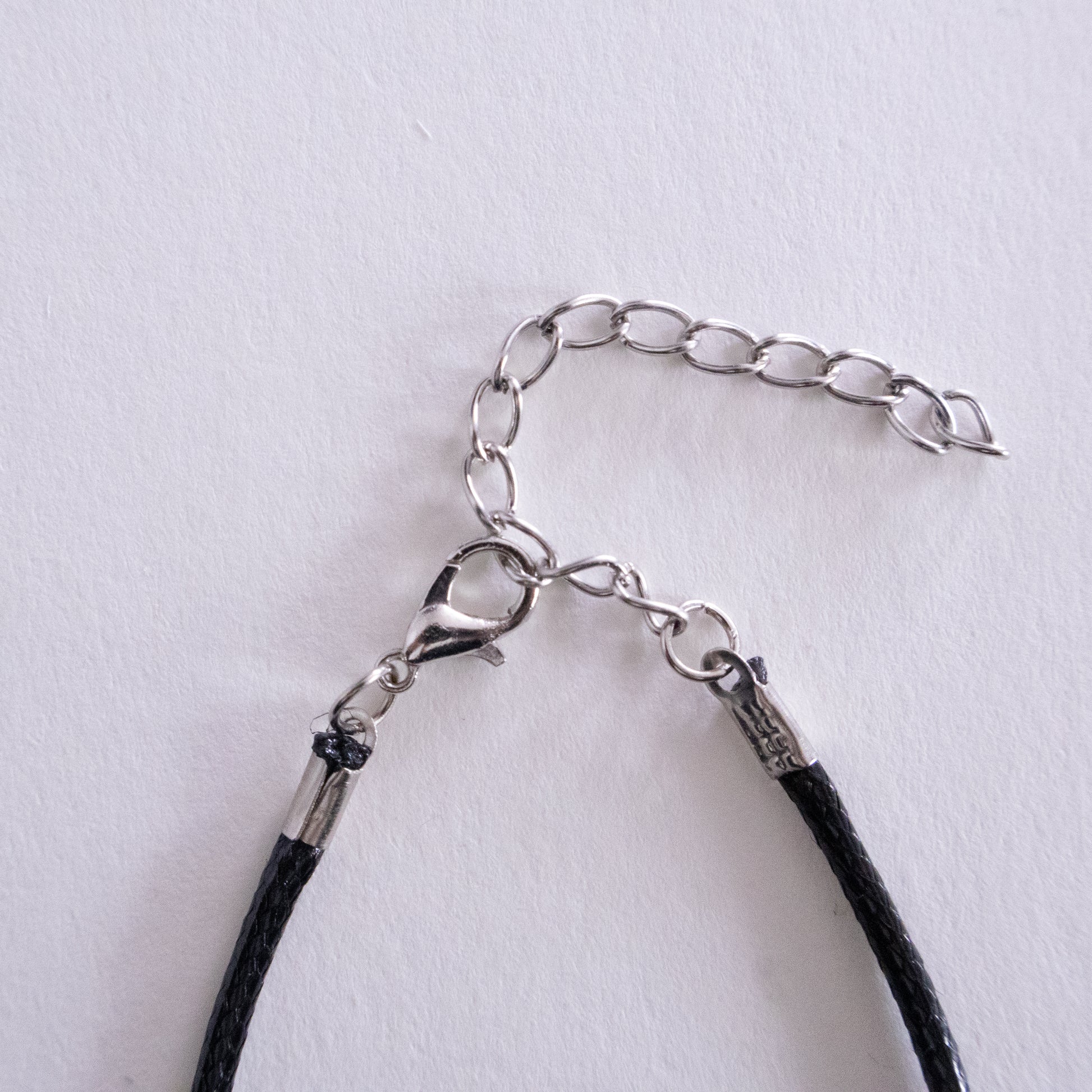 Silver necklace with a heart-shaped pendant on a beige background