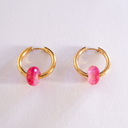Gold hoop earrings with pink beads on a white background
