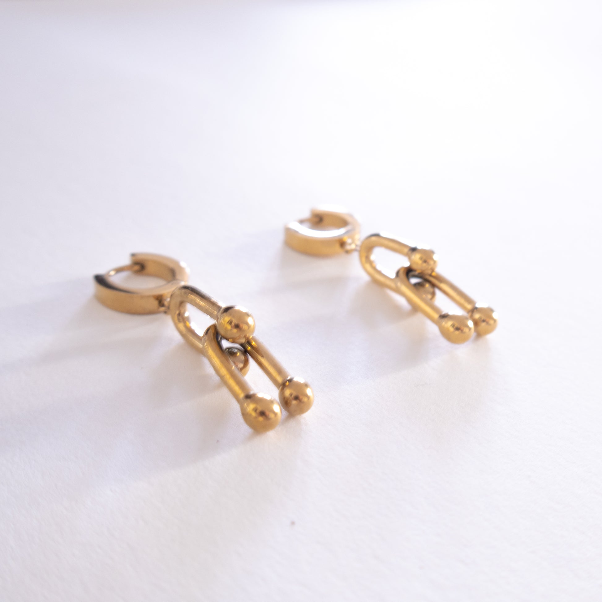 Gold chain-style earrings on a white background