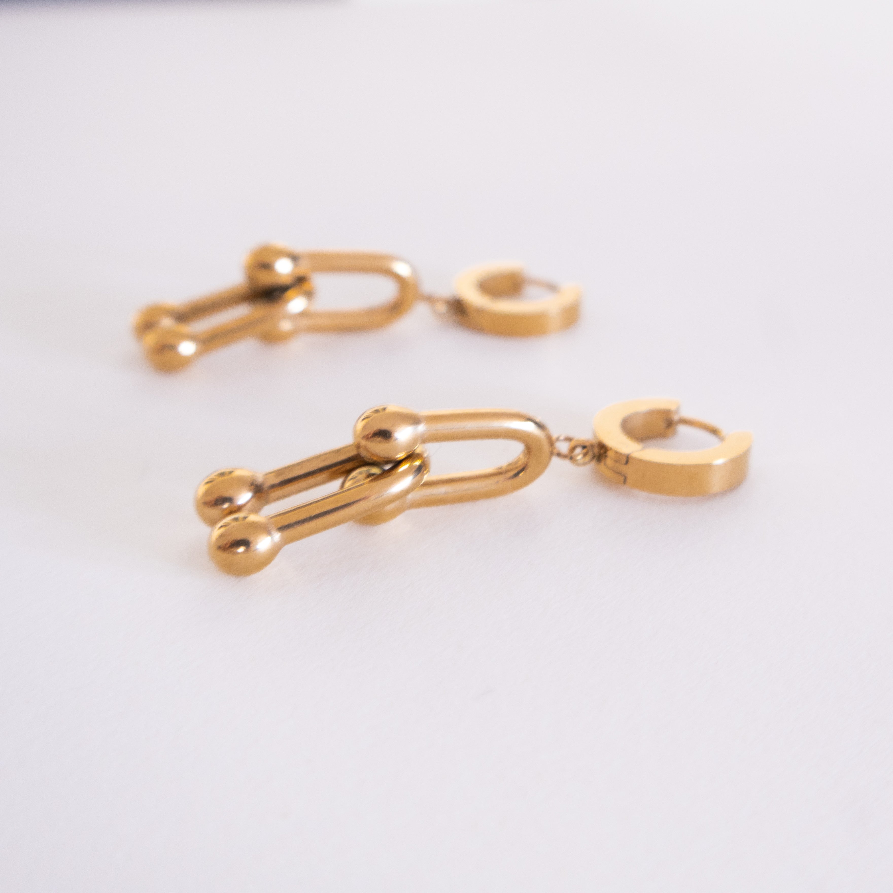 Gold chain earring on a light gray background