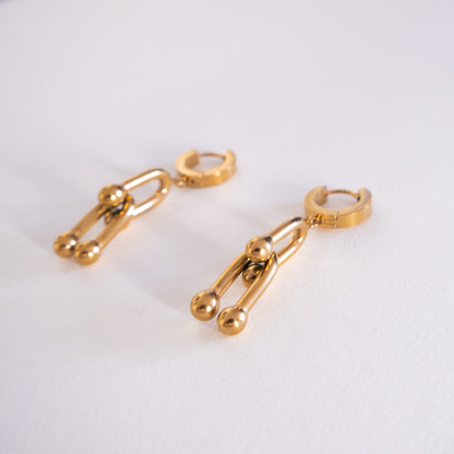 Gold hoop earrings with chain and ball details on a white background