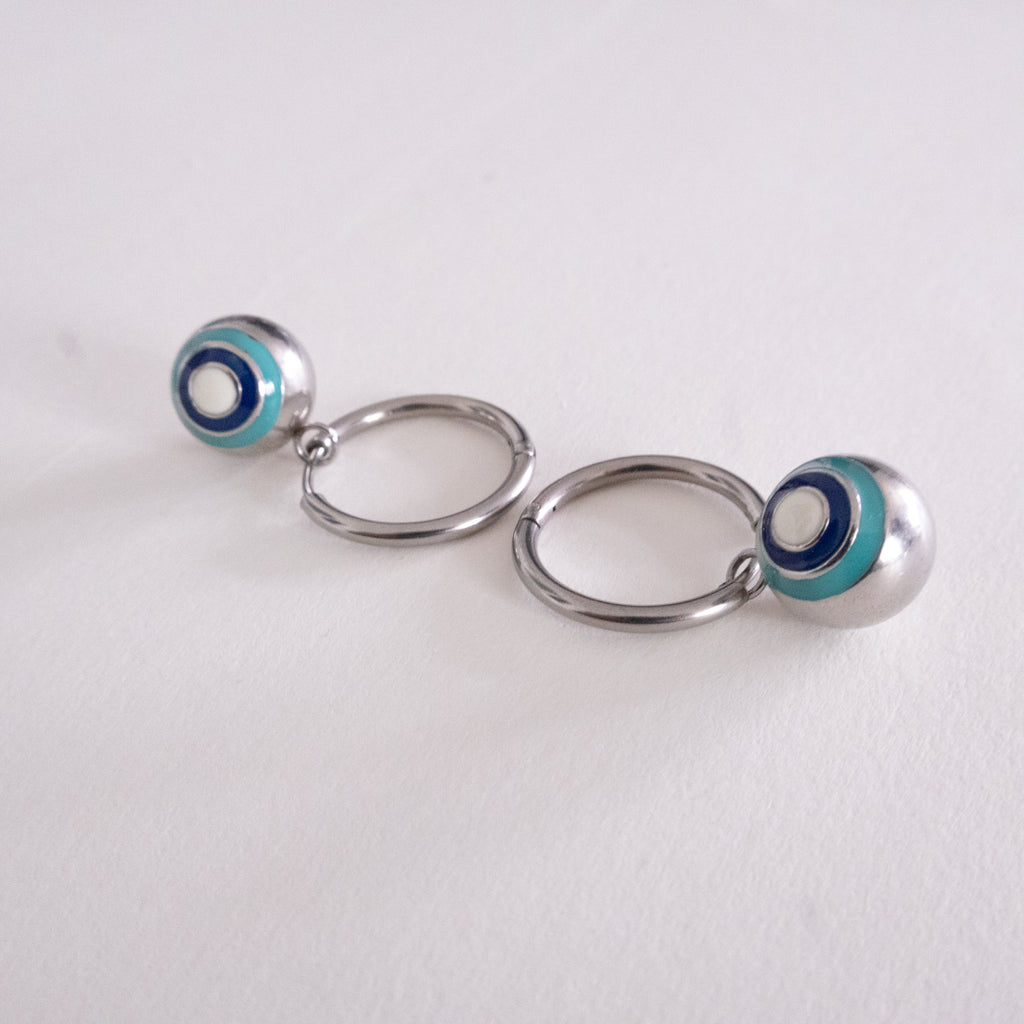 Pair of silver hoop earrings with blue and white circular accents on a light gray background