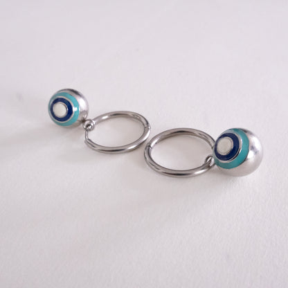 Pair of silver hoop earrings with blue and white circular accents on a light gray background
