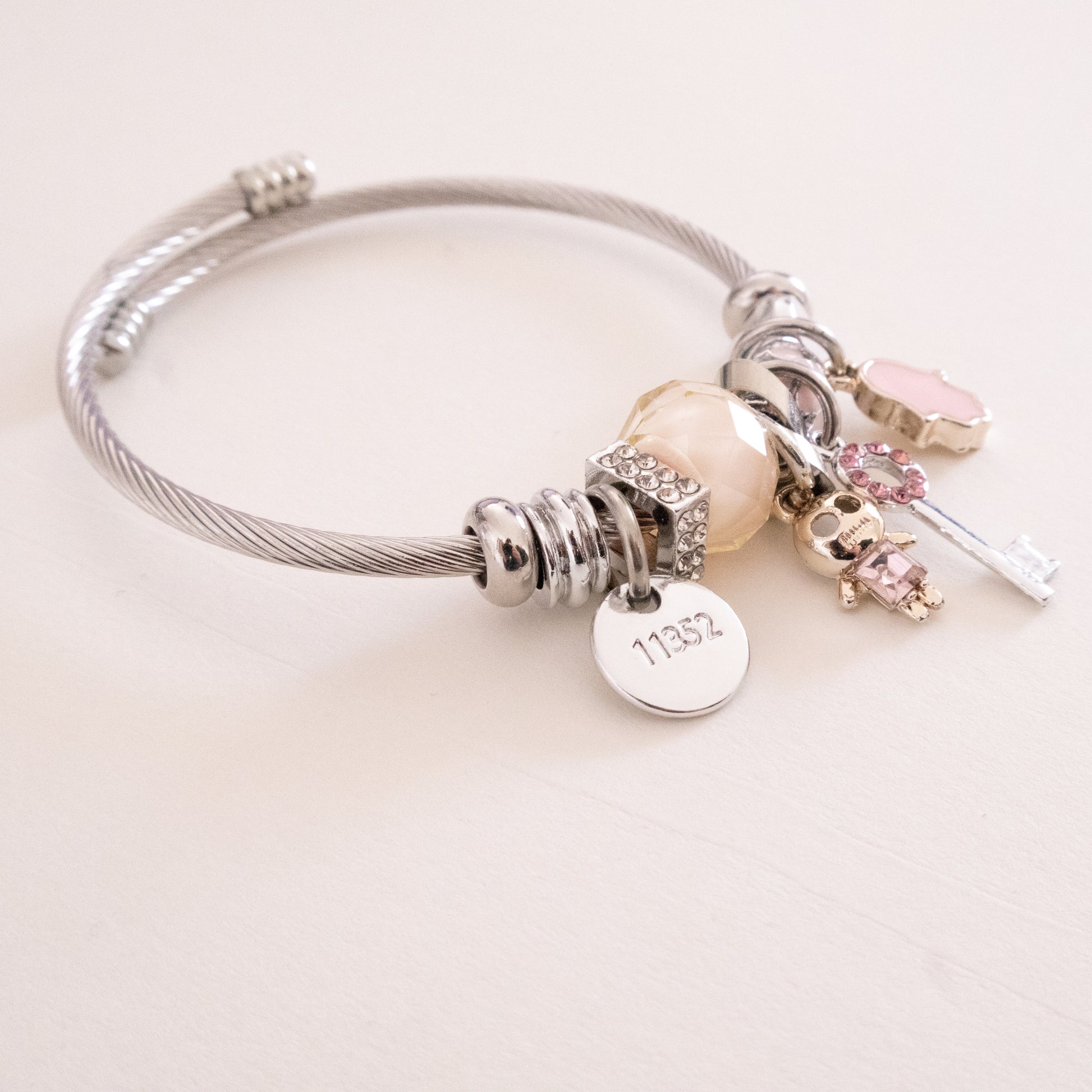 Silver bracelet with various charms on a light background