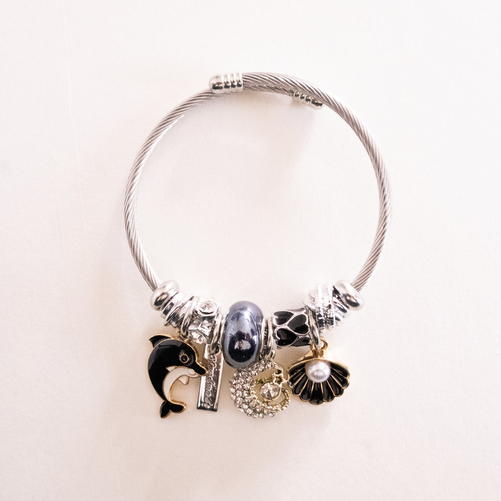 Silver bracelet with various charms on a light beige background