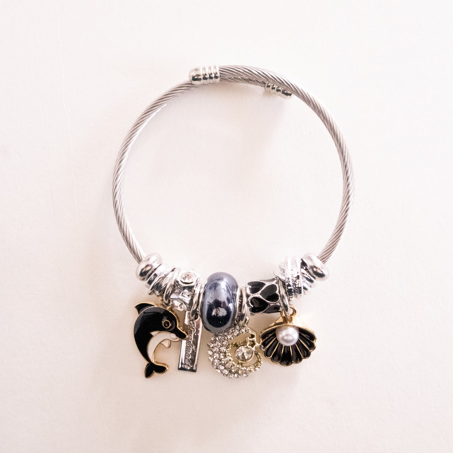 Silver bracelet with various charms on a light beige background