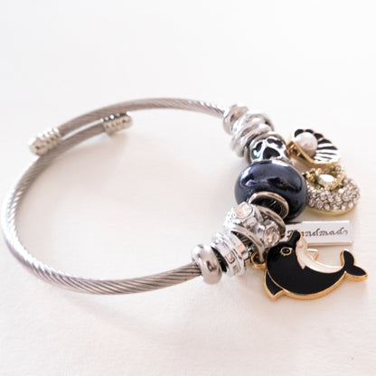 Silver bracelet with various charms on a white background