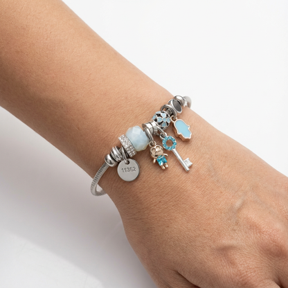 Silver bracelet with various charms on a wrist against a white background