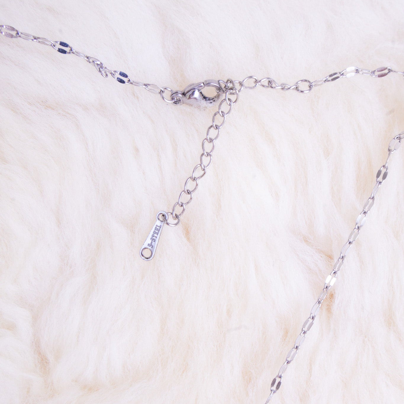 Silver chain necklace on a textured white surface