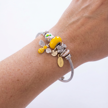 Silver bracelet with various charms on a wrist against a white background