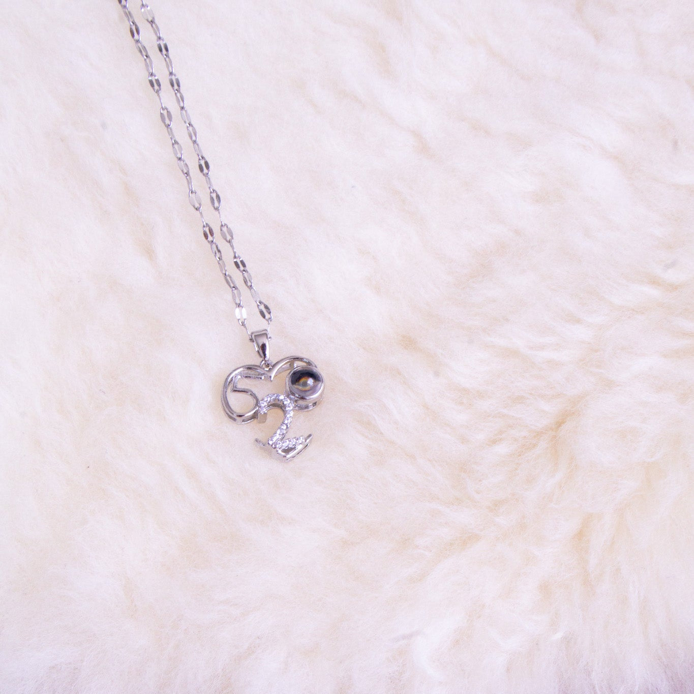 Silver necklace with a bow pendant on a white fur surface
