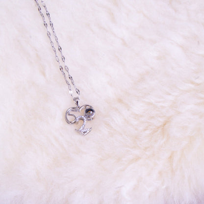 Silver necklace with a bow pendant on a white fur surface