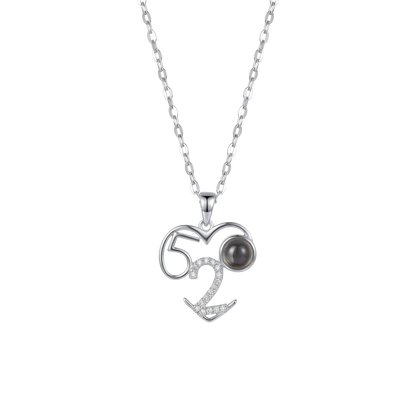 Silver necklace with a heart-shaped pendant featuring the number 52 and a black gemstone on a white background.