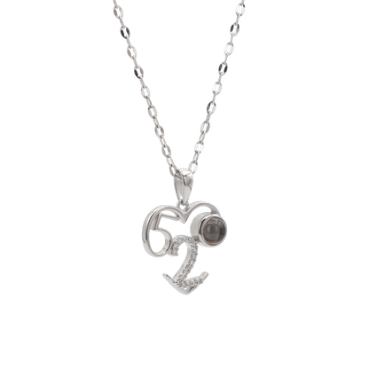 Silver necklace with a heart-shaped pendant featuring the number 62 and a small gemstone on a white background.