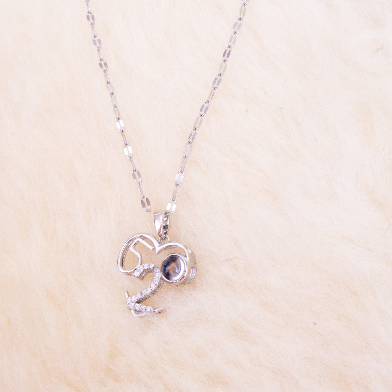Silver necklace with a heart-shaped pendant on a beige background