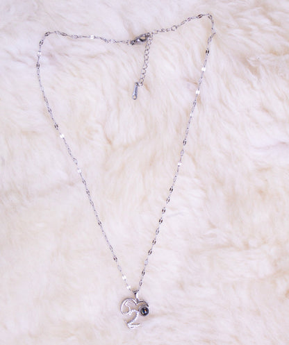 Silver necklace with a heart pendant on a white fur surface
