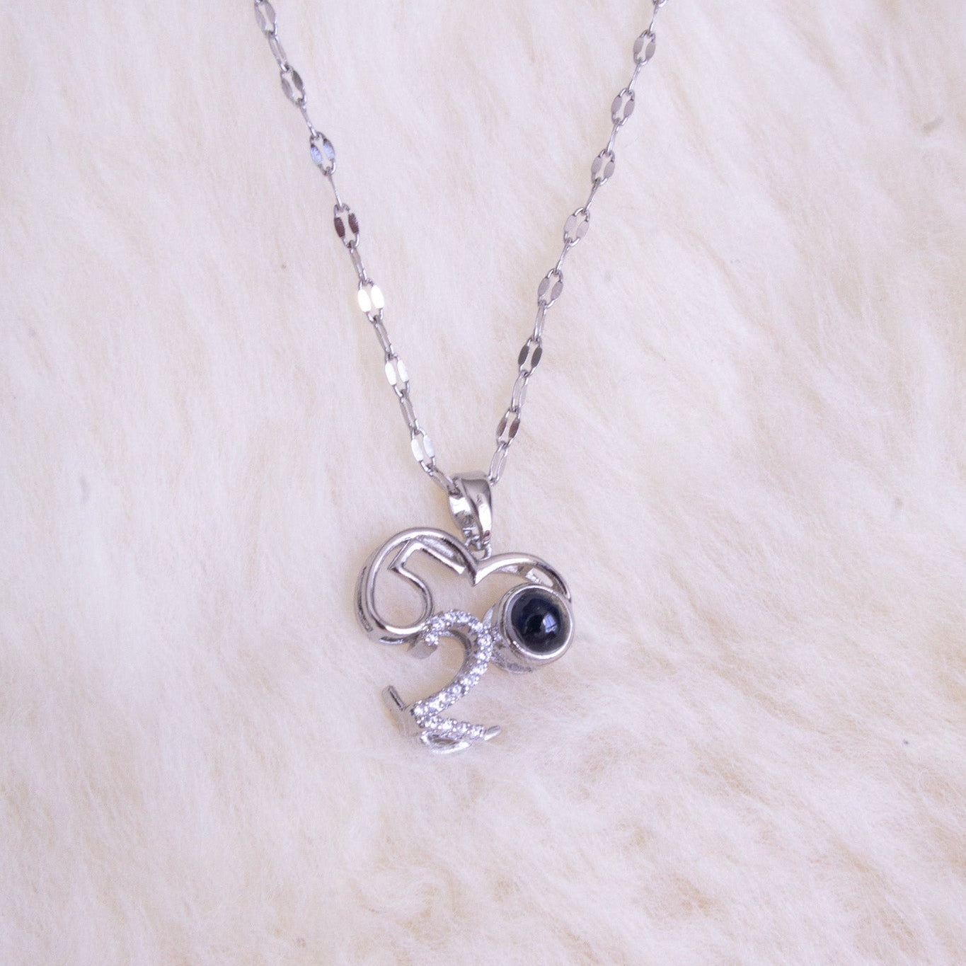 Silver necklace with a pendant featuring a black gemstone on a white fur background