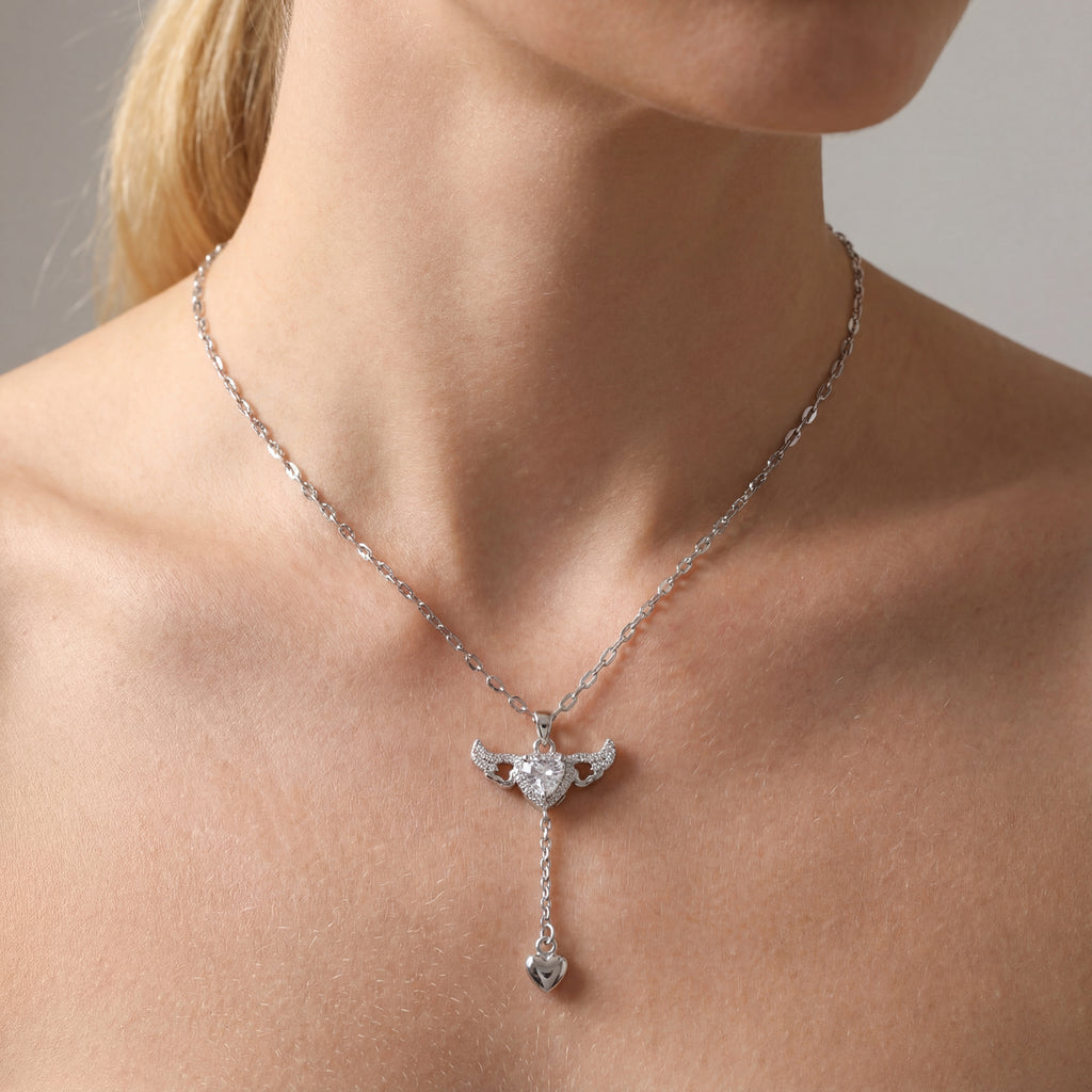 Silver necklace with a pendant on a person's neck against a neutral background